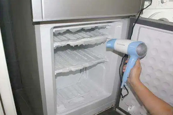 remove ice and defrost a frozen refrigerator by blowing air from hair dryer